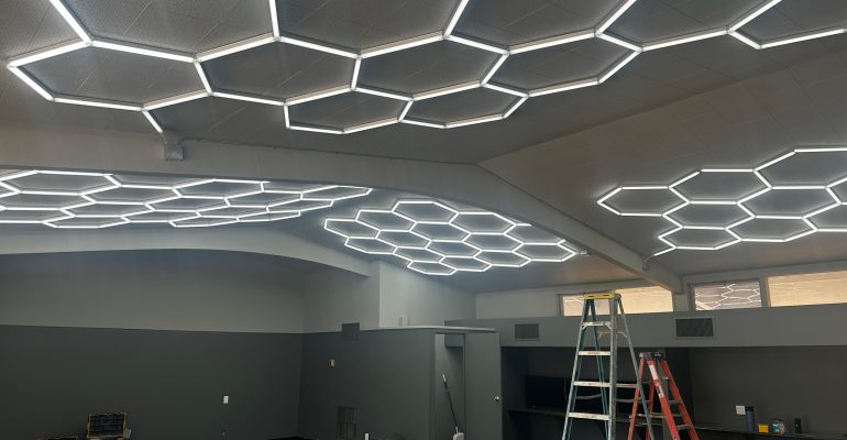 Modern hexagon honeycomb lighting installed in The Hub student center at Sonrise Christian High School, creating a warm and inviting atmosphere for high school students.
