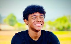 Smiling student wearing a black Sonrise Christian High School shirt sitting warmly at a table